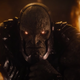 Darkseid strokes his chin in thought while lava bursts behind him.